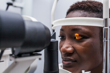Black woman in optometry cabinet using a retinograph