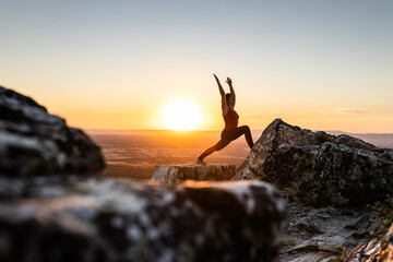 Woman doing yoga outdoors at sunset light