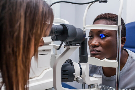 Black woman in optometry cabinet using a retinograph