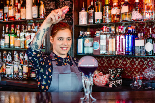 Content bartender preparing flavor blaster cocktail in bar