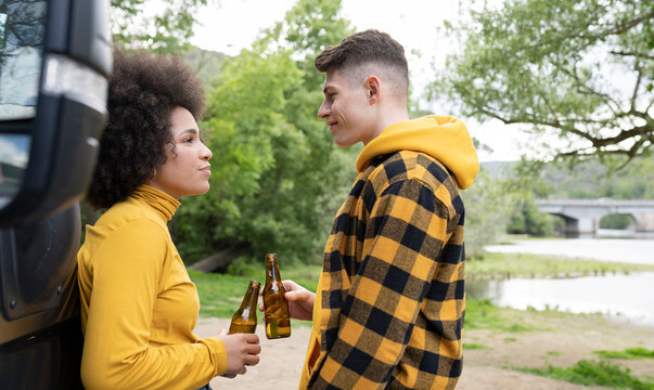 Diverse couple drinking beer in countryside