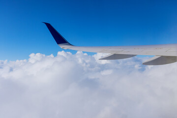 Fototapeta na wymiar Wing of an airplane flying above the clouds of an aircraft