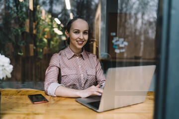 Smiling female freelancer using laptop in cafe