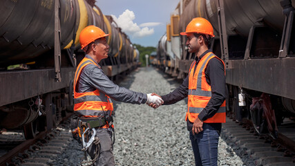Engineers check hand, senior engineer and junior engineer check hand on freight train background  