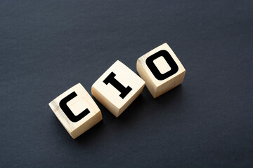 CIO written on wooden cubes - arranged in a vertical pyramid, grey and black background, CIO - short for Chief Information Investment Officer, business concept - obrazy, fototapety, plakaty