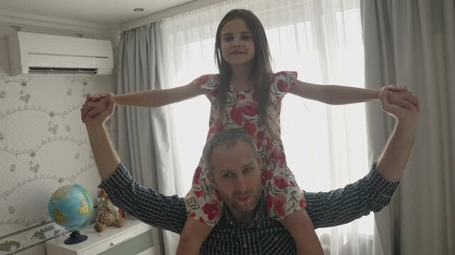 Smiling father having fun spinning dancing with cute child daughter in living room. Happy dad and small kid girl playing enjoying time together at home