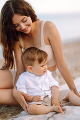 Mother with a child have fun outdoors playing games love each other. Young family with little baby boy spending time together on the beach. Family, childhood, active lifestyle concept.