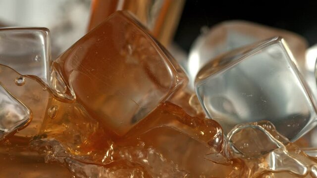 Super Slow Motion Detail Shot of Pouring Ice Coffee into Glass with Ice Cubes at 1000 fps.
