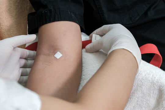 Close up of nurse hand applying adhesive plaster on arm of patient after blood collection in the hospital