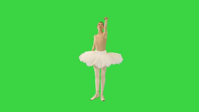 Young ballerina walks demi-pointe raising arms on a Green Screen, Chroma Key.