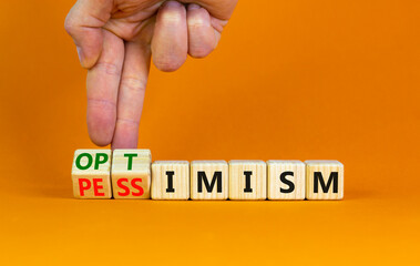 Pessimism or optimism symbol. Businessman turns cubes and changes the word 'pessimism' to...