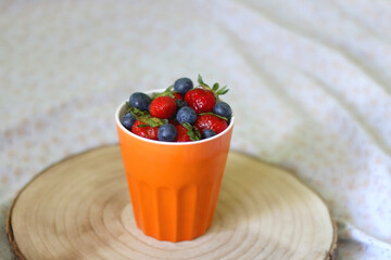 Cup of blueberries and strawberries on a bed. Selective focus.