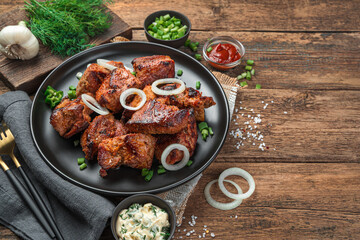 Barbecue, kebab, fried meat laid out on a plate with onions and fresh herbs.