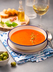 Spanish dish gazpacho in a white plate on a napkin with a pattern and a glass of wine