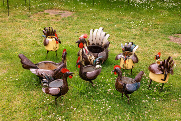 Whimsical sculptures of chickens made of recycled kitchen pots displayed in a park.