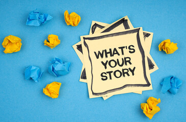 On a blue background, there are pieces of paper and a sticker with the inscription - WHAT S YOUR STORY