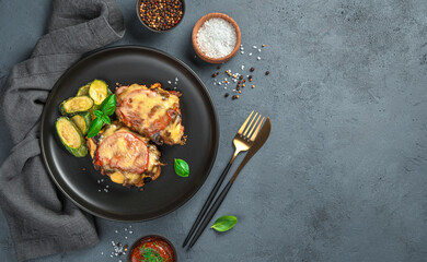 Baked meat with mushrooms, tomatoes and cheese on a gray background with spices and a linen napkin.