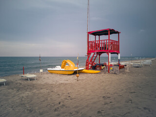 Desolate beach in Viareggio with a lifeguard facility and a pedal boat. The sky is cloudy and ready...