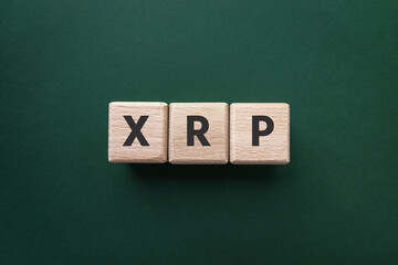 Text XRP on wooden cubes on green background. Ripple. Crypto currency. Buy and sell. Top view, flat lay.