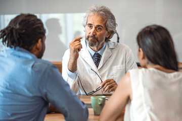 Fototapeta premium Cropped shot of a young couple having a consultation with their doctor. Shot of a doctor having a consultation with a couple in a clinic. Young couple during the consultations at clinic.