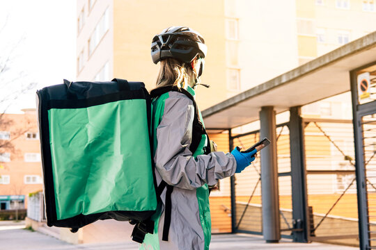 Female courier with parcels using smartphone