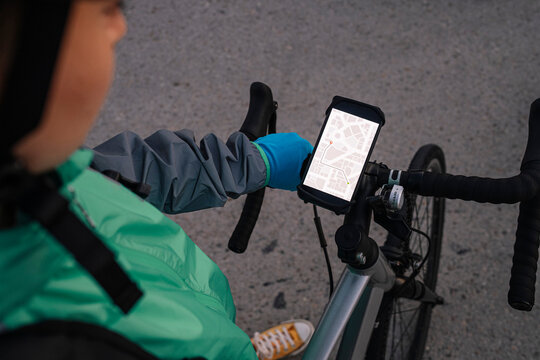 Crop courier reading GPS map on bike handlebar