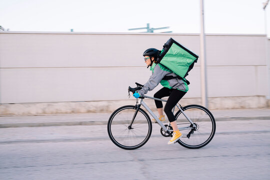 Delivery woman riding bicycle on street