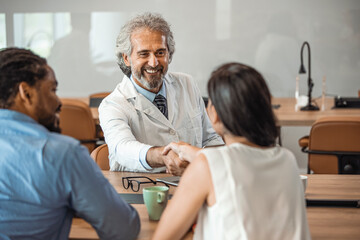 Doctor shaking hands with woman. Female patient visiting health professional. They are in hospital. Cropped shot of a handsome mature male doctor and his patient shaking hands in the hospital