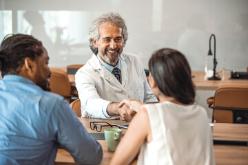 Obraz premium Doctor shaking hands with woman. Female patient visiting health professional. They are in hospital. Cropped shot of a handsome mature male doctor and his patient shaking hands in the hospital