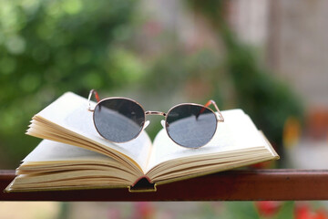 Open book and retro sunglasses in a garden. Selective focus.