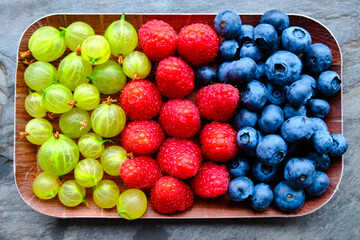 Blueberries, raspberries and grapes on slate background