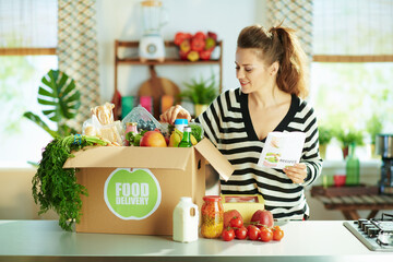 happy modern housewife with food box in kitchen