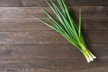 bunch of fresh green onion on wooden table, top view. Copy space for text.