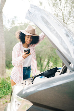 Black woman having troubles with car during trip in nature