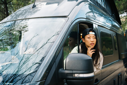 Ethnic woman looking out car window in nature