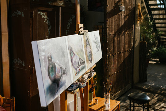 Pigeons painting on canvas on easel in workshop