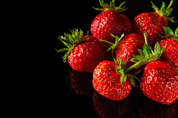 Lot of red ripe strawberries on a black background. Summer diet and vitamin set idea. Free advertising space