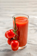 A glass of tomato juice and a branch of small tomatoes banner. Cherry tomatoes in a red plate on a...