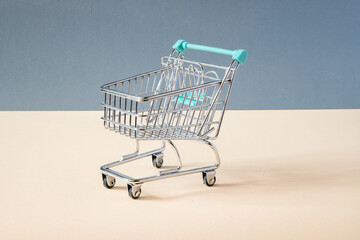 SMALL TOY OF A SHOPPING CART  ON BLUE BACKGROUND AND YELLOW FLOOR