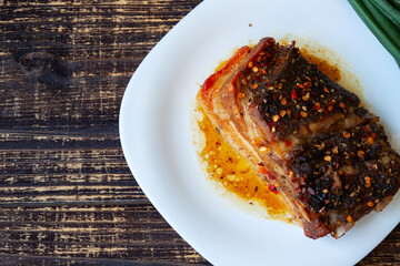 Spicy fried brisket with interlayers of pork lard, baked with herbs and paprika, on a dark background