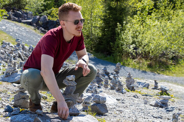 man with a red beard is squatting against of many stones