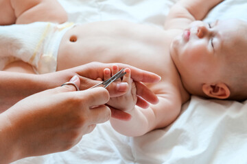Baby getting fingernails cut while sleeping by his mother with scissors. Nursing a child. Clipping....