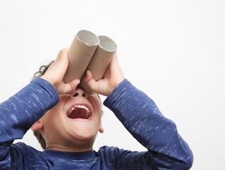 boy looking  through toy binoculars toilet paper roll on white background