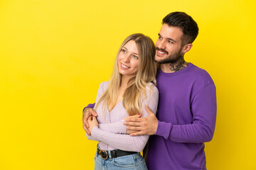 Fototapeta premium Young couple over isolated yellow background looking to the side