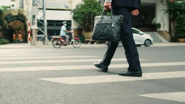 Close up rear view of a hurry aucasian middle aged business man in leather shoes and suit on the way to the office building,businessman in a suit crosses the road on a zebra crossing, man gets to work