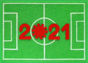 Red felt year numbers 2021, zero in the form of a corona virus, placed on mini football field made of green felt, top view. Concept about soccer championship during covid pandemic. - obrazy, fototapety, plakaty