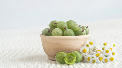 gooseberries and flowers. ripe berries on a white tablecloth