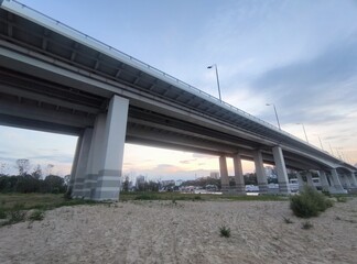 Automobile bridge over the river in the evening. Sandy shore