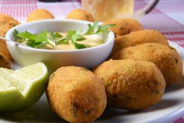 delicious fried cod dumpling with herb sauce on the table on blurred dark background.