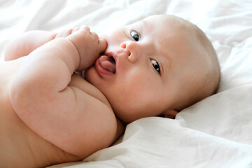 Close-up Portrait of a beautiful Baby on white. Head and Face. Newborn Baby lying on its side and looks into the Camera. Motherhood, health, pediatrics concept. Cute and adorable Infant